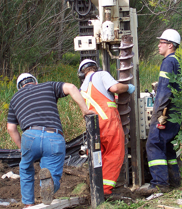 persons using equipment to drill a well