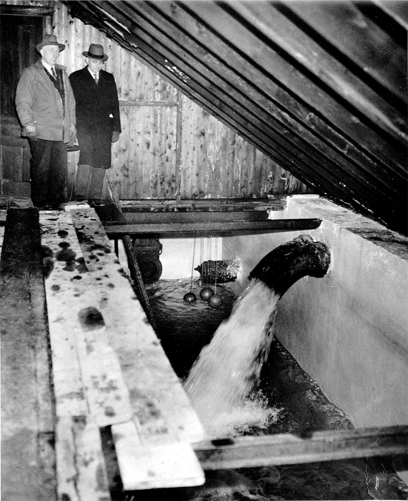 Two people looking at wood reservoir inside the Middleton Water Pumping Station.